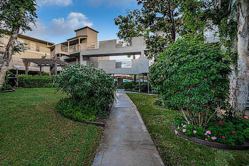 A concrete pathway leads to a building surrounded by greenery.