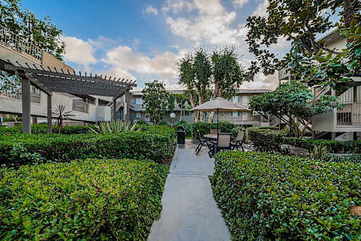 A pathway leads through a landscaped courtyard with a pavilion in the background.
