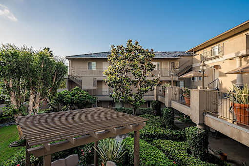 A wooden deck is in the middle of a grassy area with a building in the background.