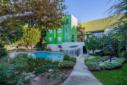 A green and yellow building with a pool in the backyard.
