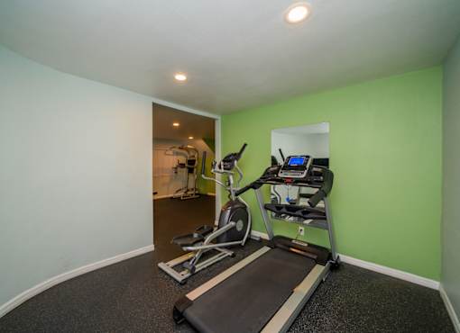 A treadmill and a stationary bike are in a room with green walls.