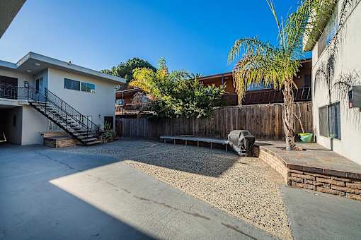 A concrete patio area with a black tarp and a wooden fence.