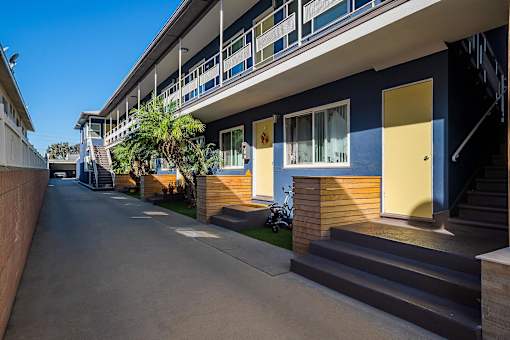 A long, narrow road leads to a building with blue and yellow walls.