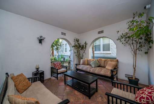 A living room with a couch, chair, and potted plant.