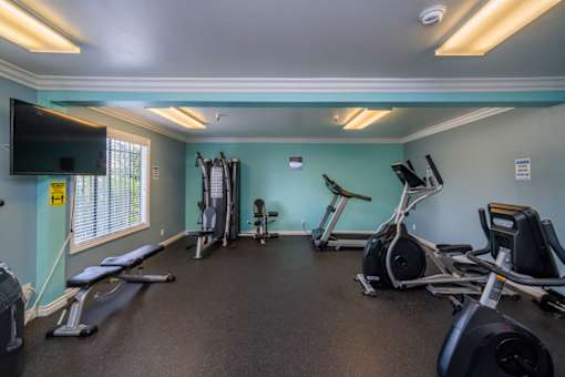 A gym with a variety of exercise equipment including treadmills, stationary bikes, and weight machines.