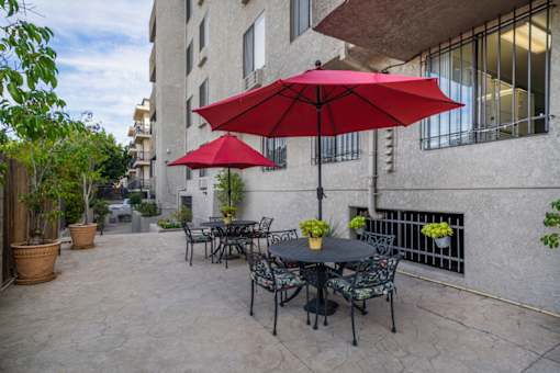 A patio with a table and chairs under a red umbrella.