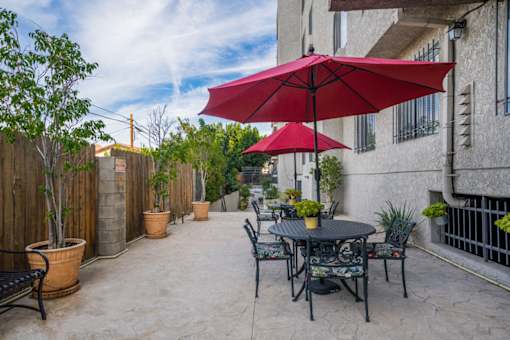 A patio with a table and chairs under a red umbrella.