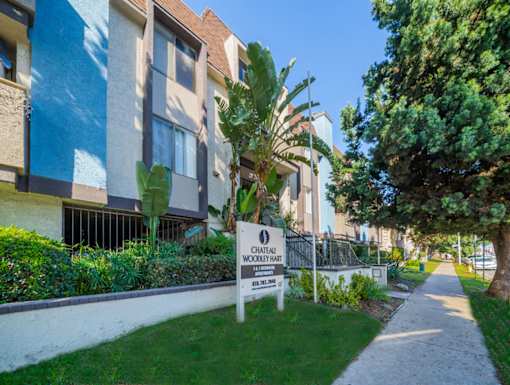 an apartment building with a sign in the grass in front