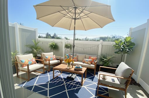A patio with a table, chairs, and an umbrella.