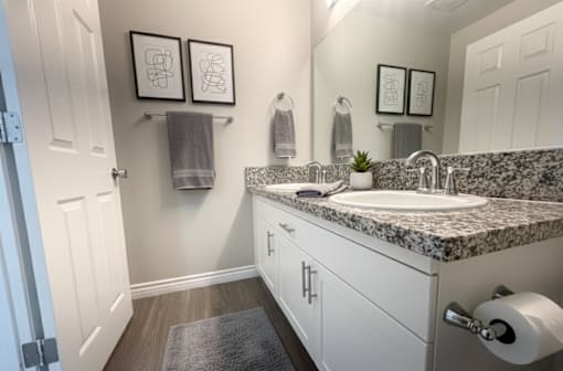 A bathroom with a marble countertop and white cabinets.