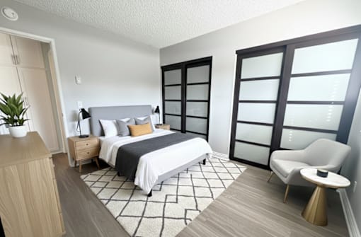A bedroom with a bed, chair, and plant.