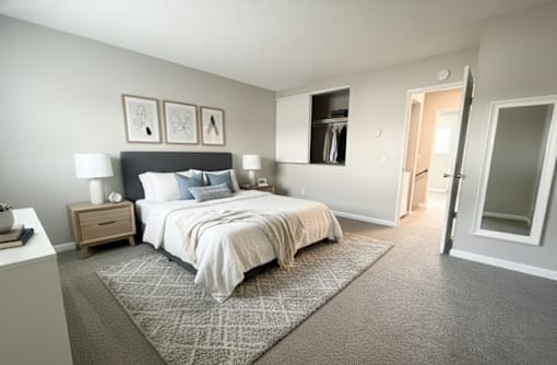 A bedroom with a large bed and a nightstand with a lamp.