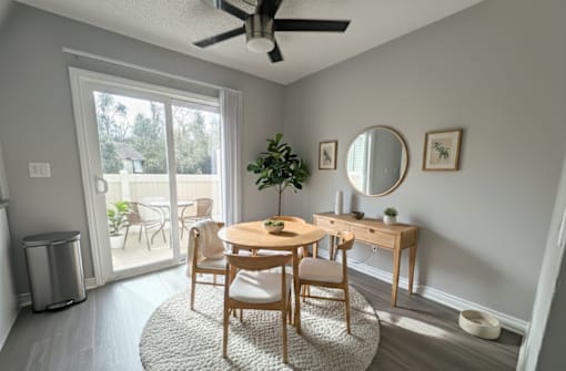 A room with a table, chairs, and a ceiling fan.