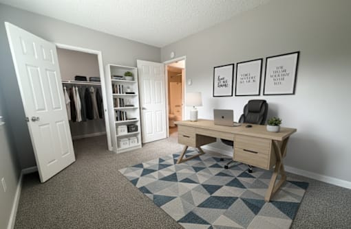 A room with a desk, chair, and a rug with a geometric pattern.