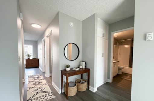A hallway with a round mirror on the wall and a table with a plant on it.