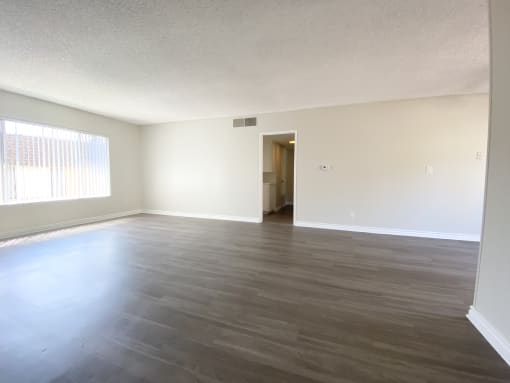 an empty living room with wood floors and a window