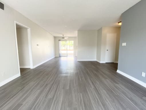the living room and dining room of an apartment with wood flooring