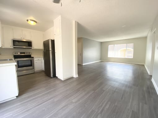 an empty kitchen and living room with a hard wood floor