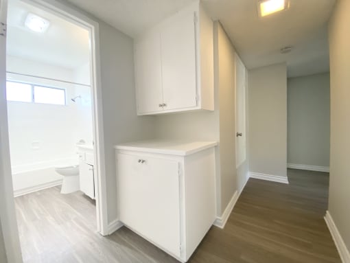 a renovated bathroom with white cabinets and a white toilet