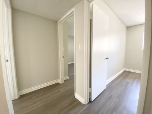 an empty living room with white walls and wood flooring