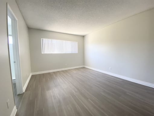 an empty living room with wooden floors and a window