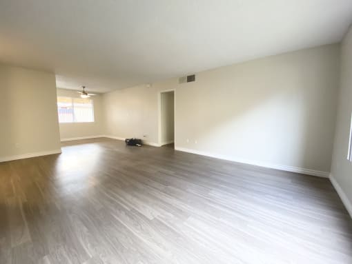 an empty living room with wood floors and white walls