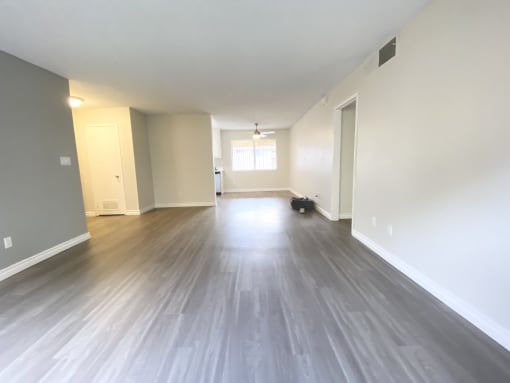 an empty living room with wood floors and white walls