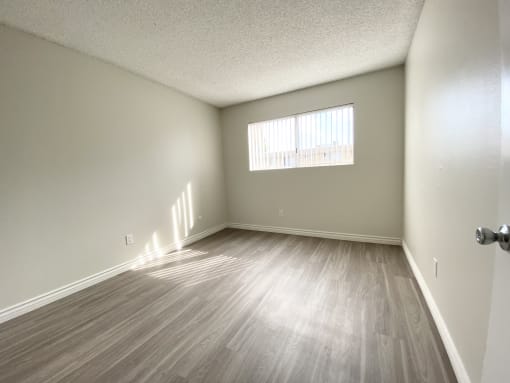 an empty living room with wood floors and a window