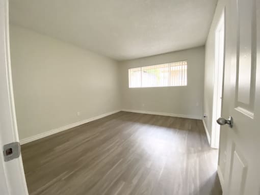 an empty living room with wood floors and a window
