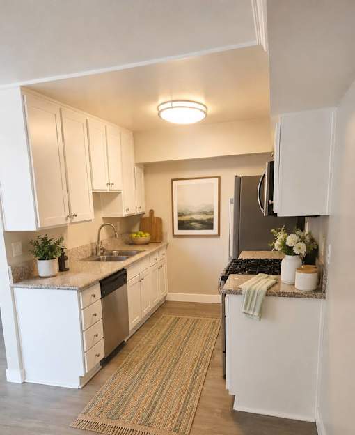 A kitchen with white cabinets and a rug on the floor.