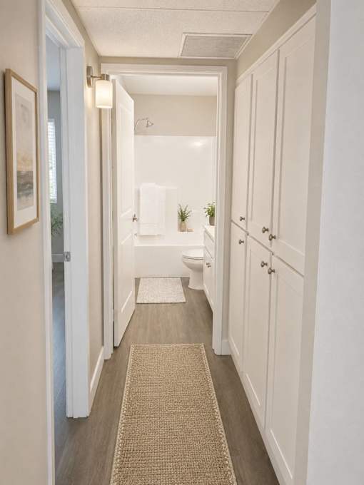 A hallway with white walls and a beige rug.