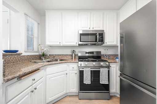 A kitchen with white cabinets and a granite countertop.
