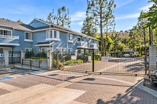 A gated entrance to a residential complex with a blue building.