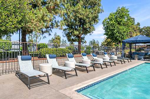 A row of lounge chairs by the pool the edge of a pool.