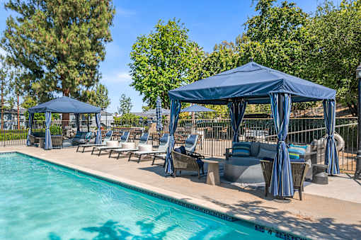 A pool area with a blue canopy and lounge chairs.