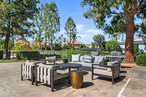 A patio with a table and chairs surrounded by trees.