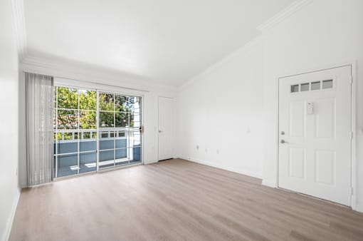 A room with a sliding glass door leading to a balcony.