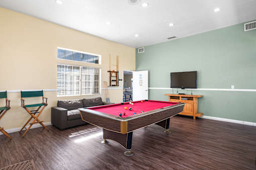 A room with a pool table and a television.