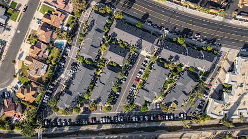 A street view of a residential area with houses and parked cars.