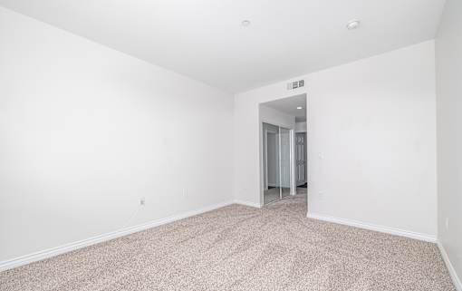 A room with a carpeted floor and a doorway leading to another room.