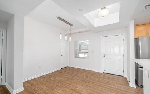 A room with white walls and wooden flooring, with a skylight above and a door to the right.
