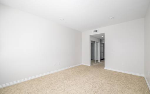A white room with a carpeted floor and a doorway leading to another room.