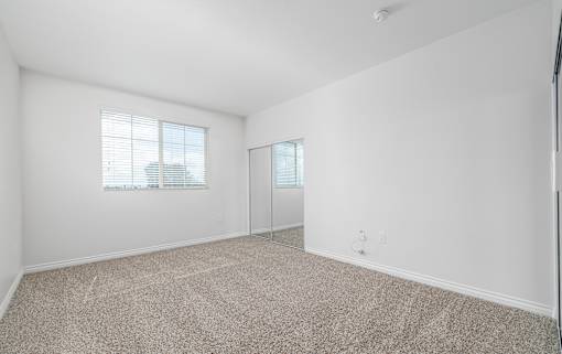 A room with a carpeted floor and a window with blinds.