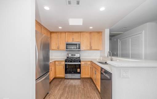 A modern kitchen with wooden cabinets and stainless steel appliances.