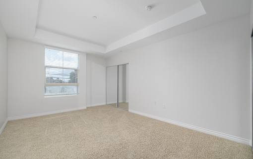 A room with a carpeted floor and a window with blinds.