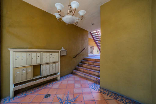 a hallway with a staircase and a yellow wall and a chandelier