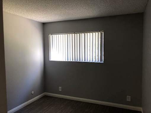 A room with a window and a wooden floor.