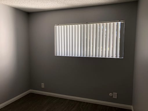 A room with a window covered by white blinds.