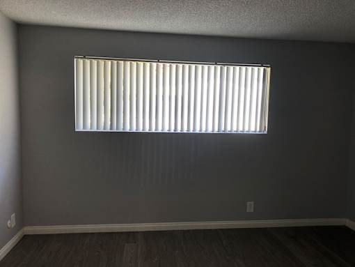 A room with a window covered by white blinds.