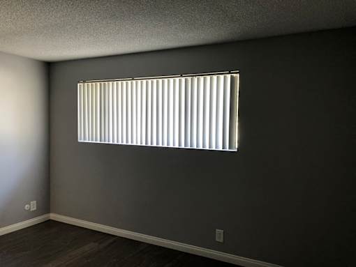 A room with a window covered by vertical blinds.